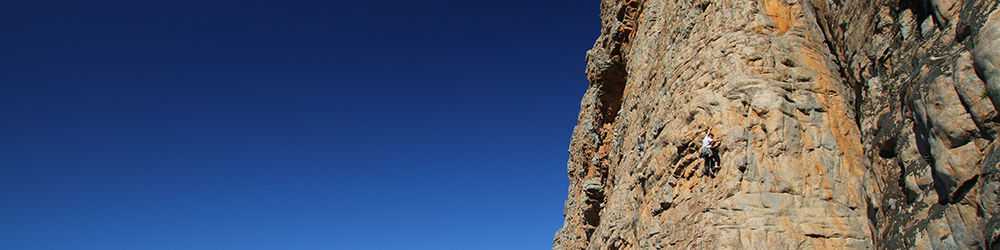 Man and woman climbing with blue sky in background
