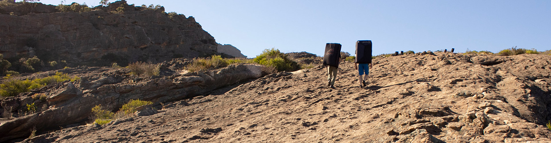 two people carrying bouldering matts on back